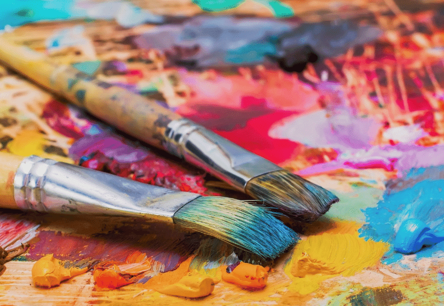 Colourful daubs of paint and paint brushes on a palette