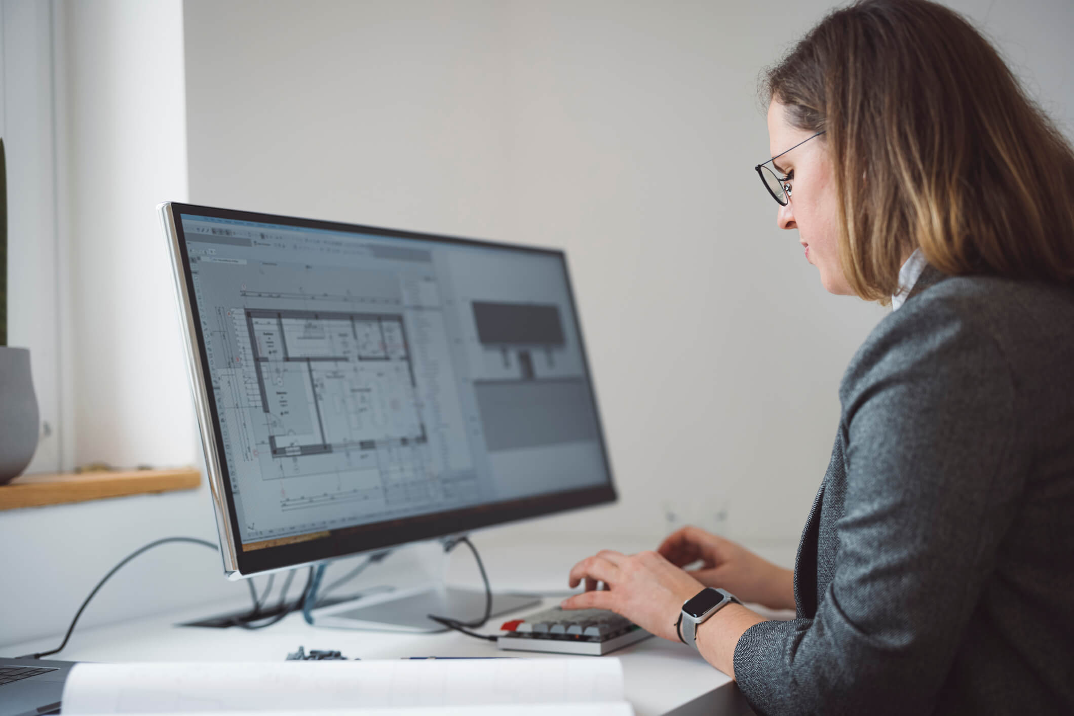 Image depicts an office setting with a man showing a woman information on a tablet.