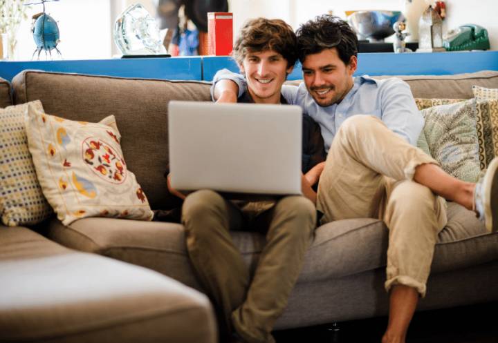 Couple sitting on couch using laptop