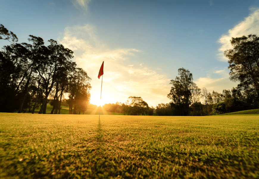Golf course with flag in hole on the green at sunrise