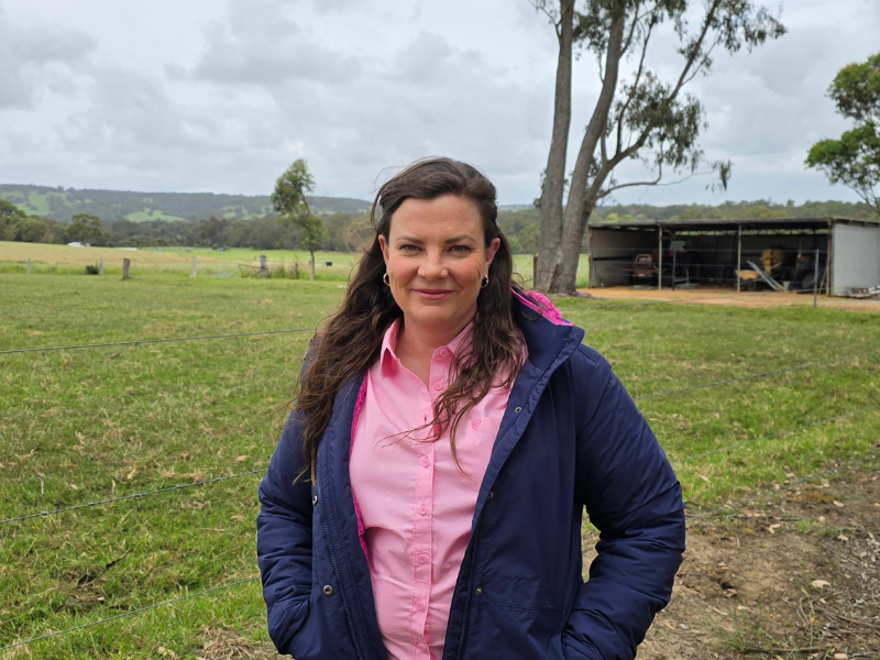 Michelle Moriarty, Founder and CEO of Grief Connect, standing in a field with a shed in the background