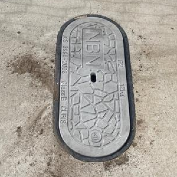 nbn underground pit lid on a footpath, providing access to underground telecommunications infrastructure.
